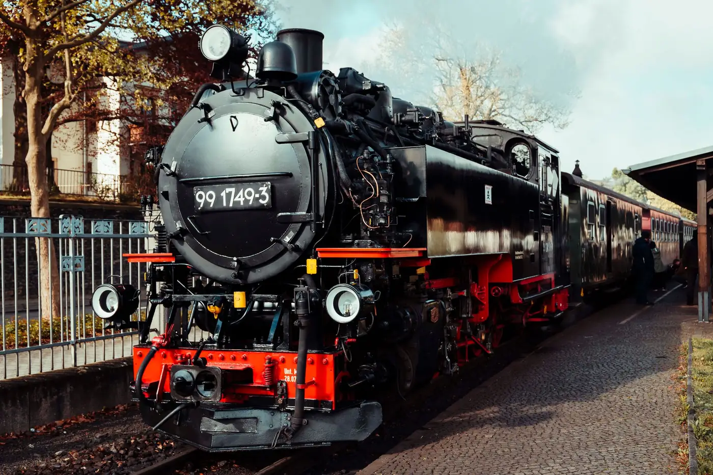 Historische stoomtrein met wagon stilstaand bij een klein station