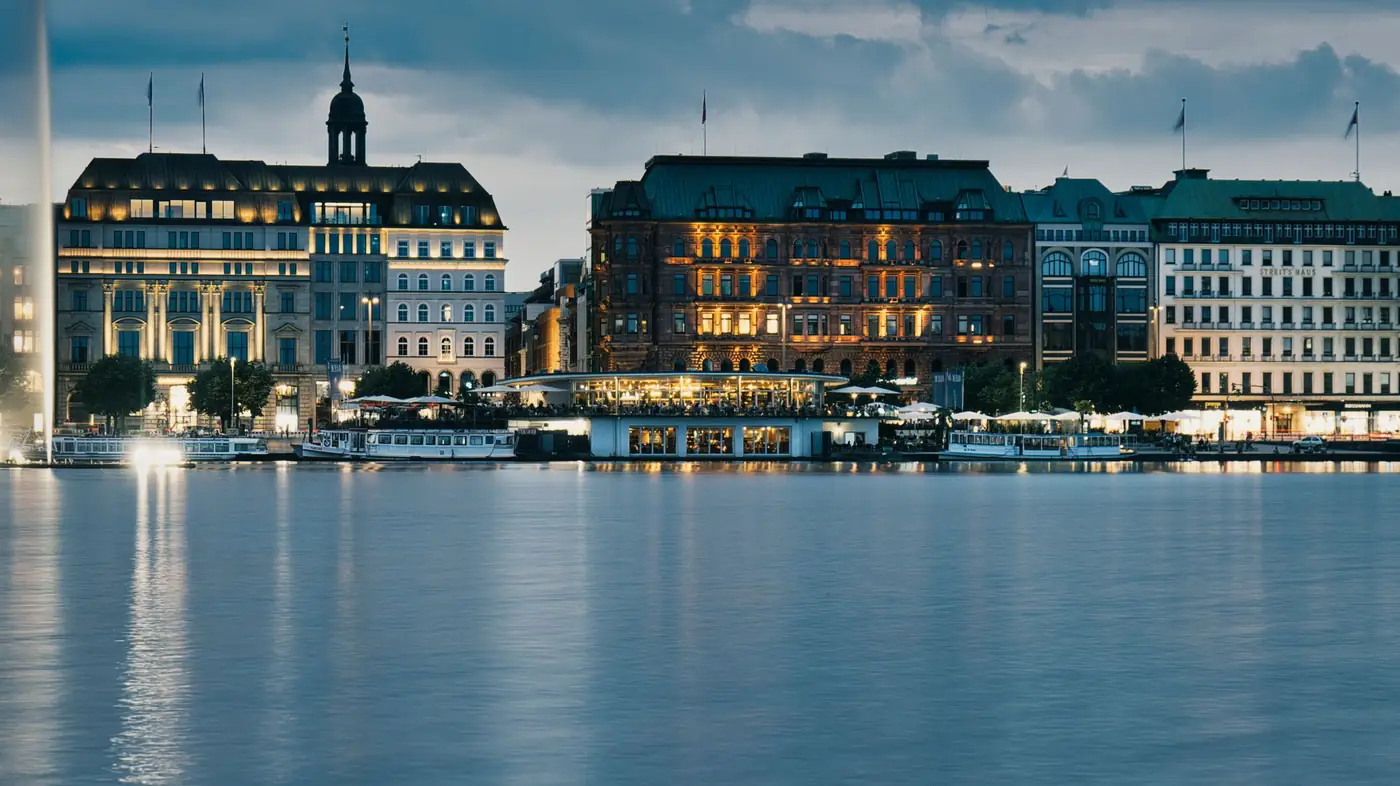 Verlichte gebouwen langs het water in Hamburg bij schemering