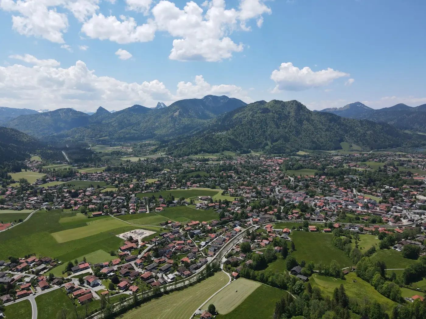 Panoramic aerial view of Tegernsee, Germany, with a scenic mountain range in the background.