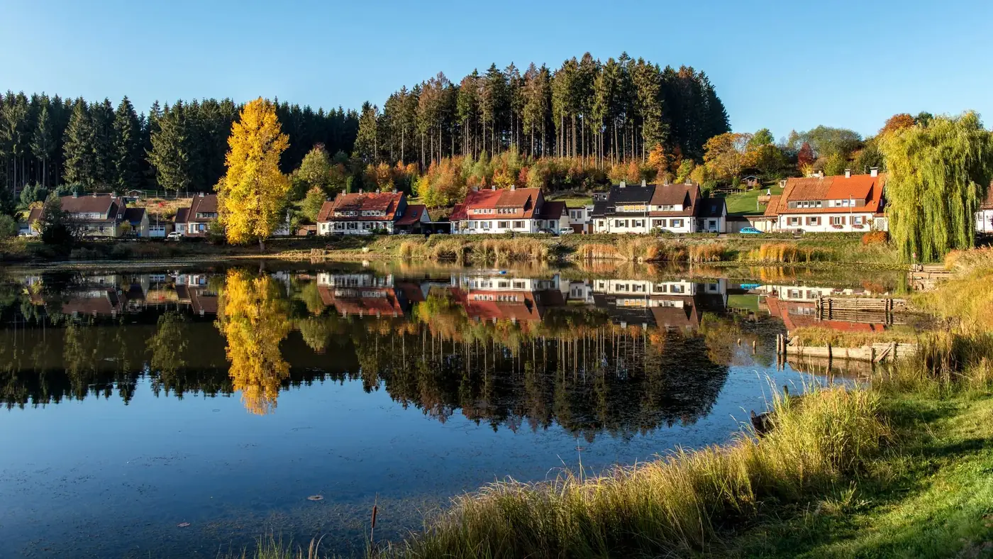 Picturesque lakeside village in autumn with forest reflections in Bad Grund, Germany.