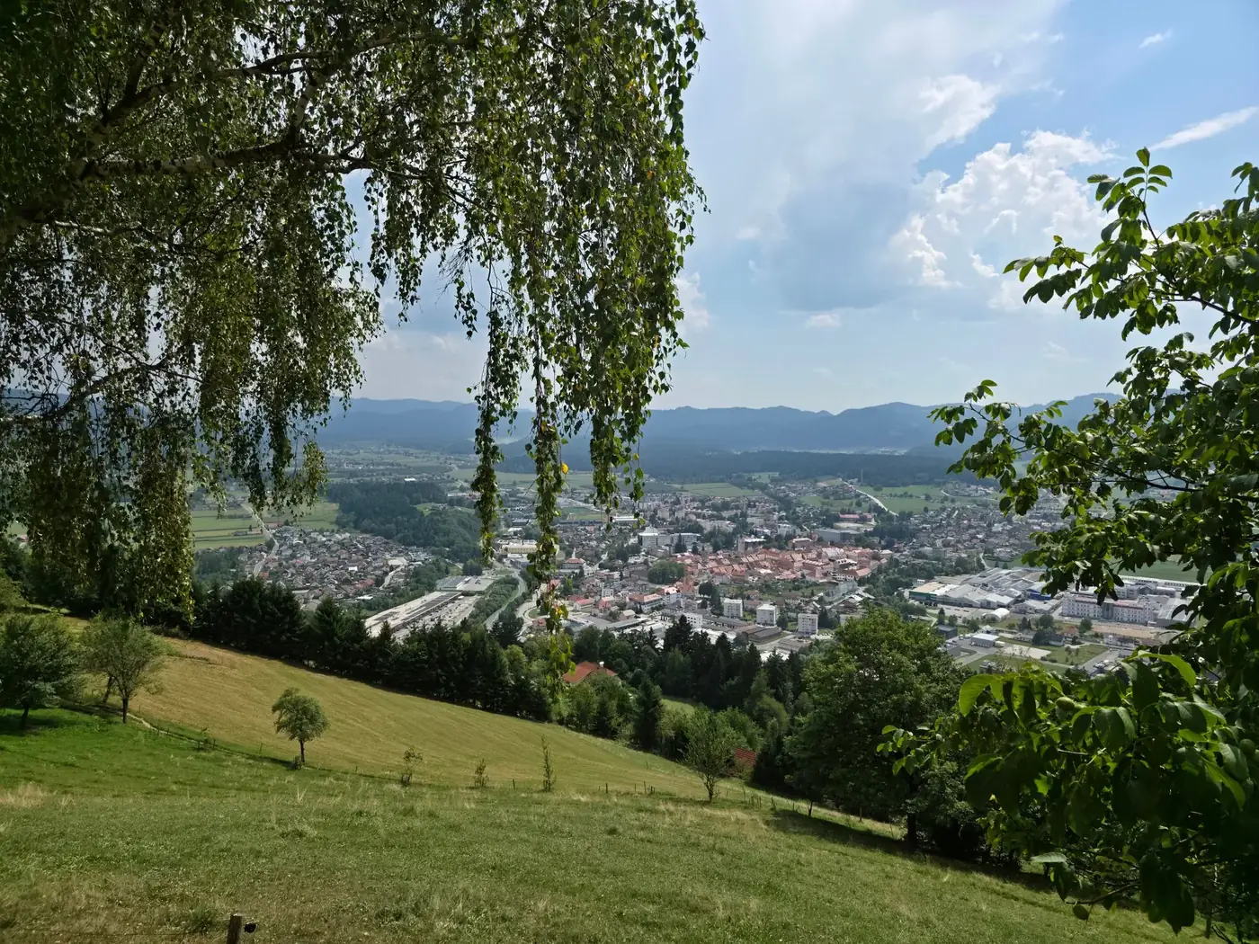 A picturesque view over a Slovenian town nestled among hills, captured in summertime.