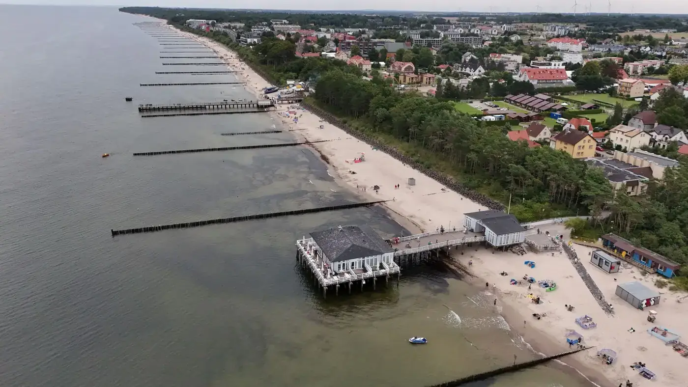 Aerial shot of a coastal town with beach, pier, and waterfront buildings.
