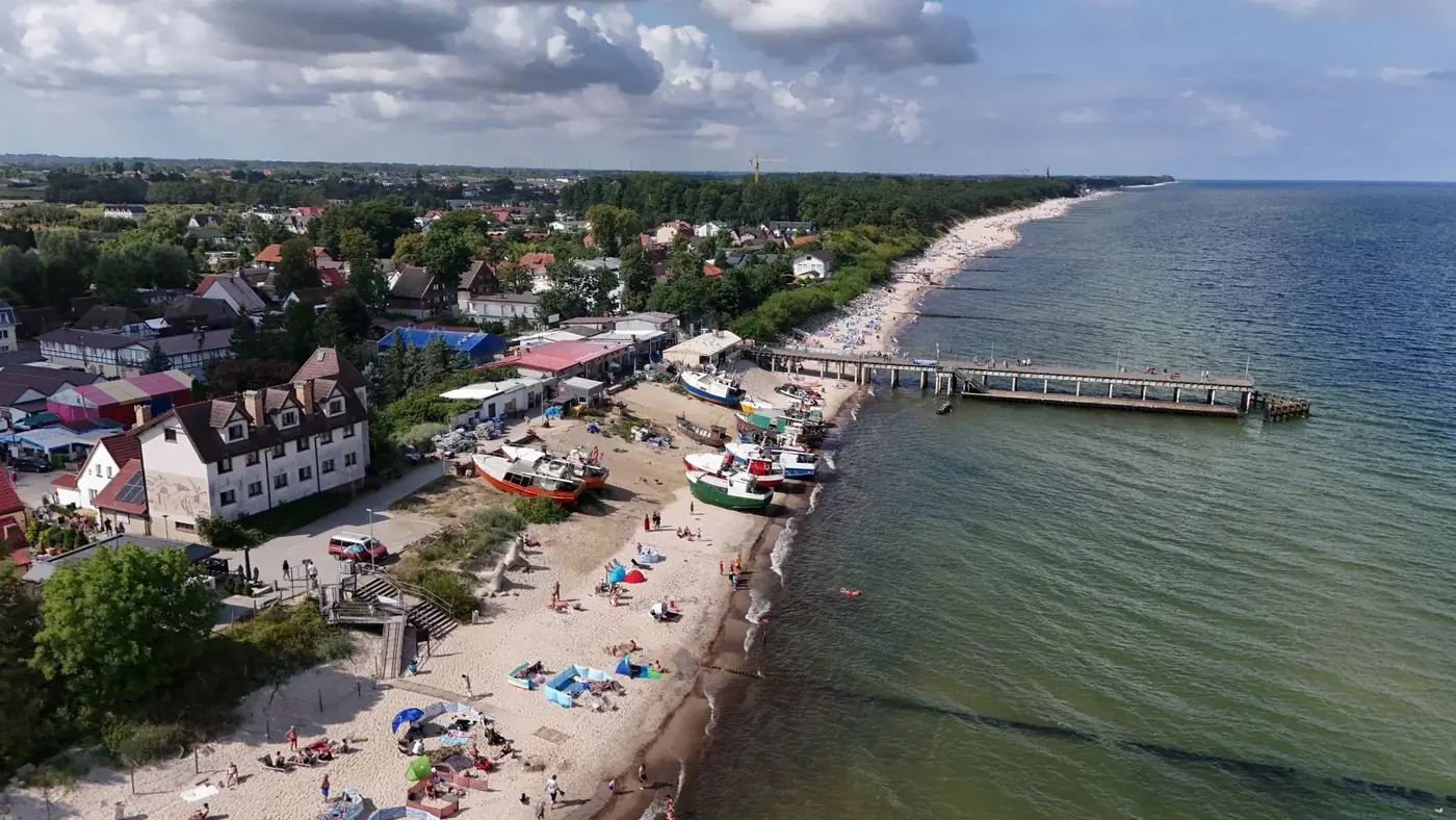 Stunning aerial view of a beachfront town with boats, beach, and a long pier.