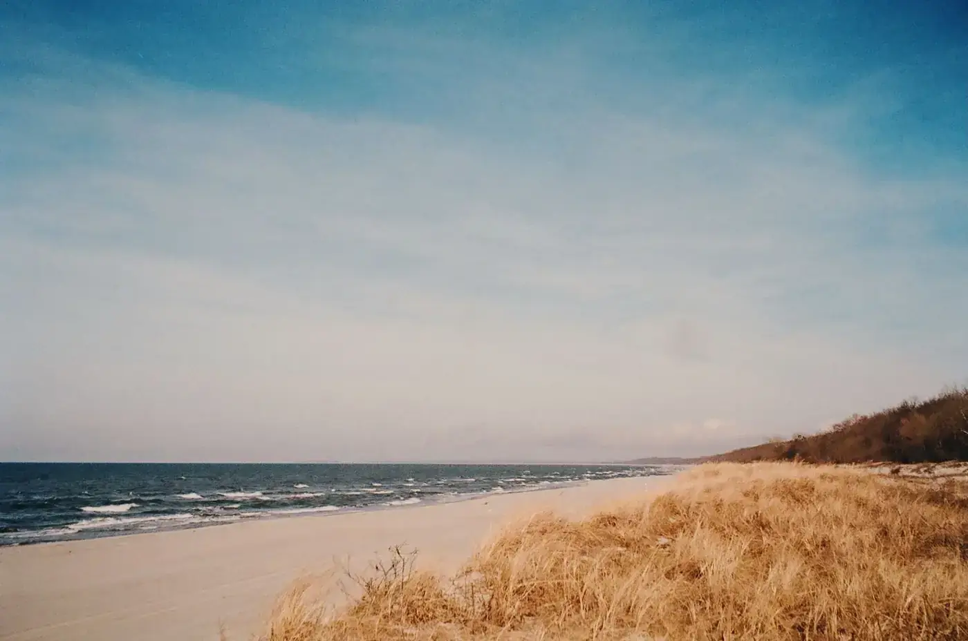 Calm ocean waves on a sandy beach under expansive blue sky. Perfect for relaxation and tranquility themes.