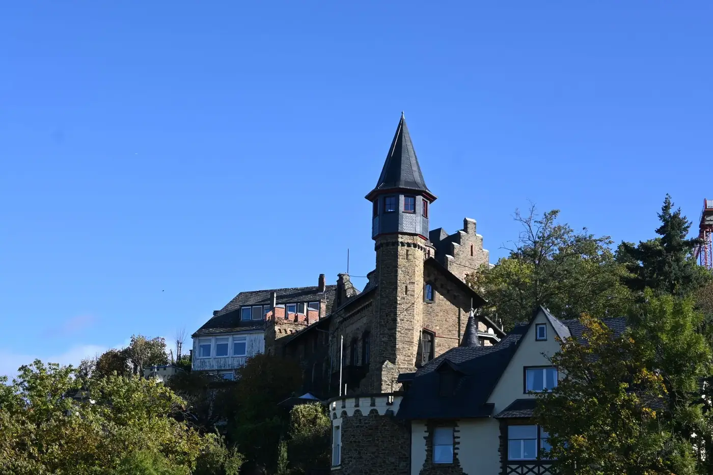 Scenic view of the historic Lahneck Castle in Lahnstein, surrounded by lush trees under a clear blue sky.