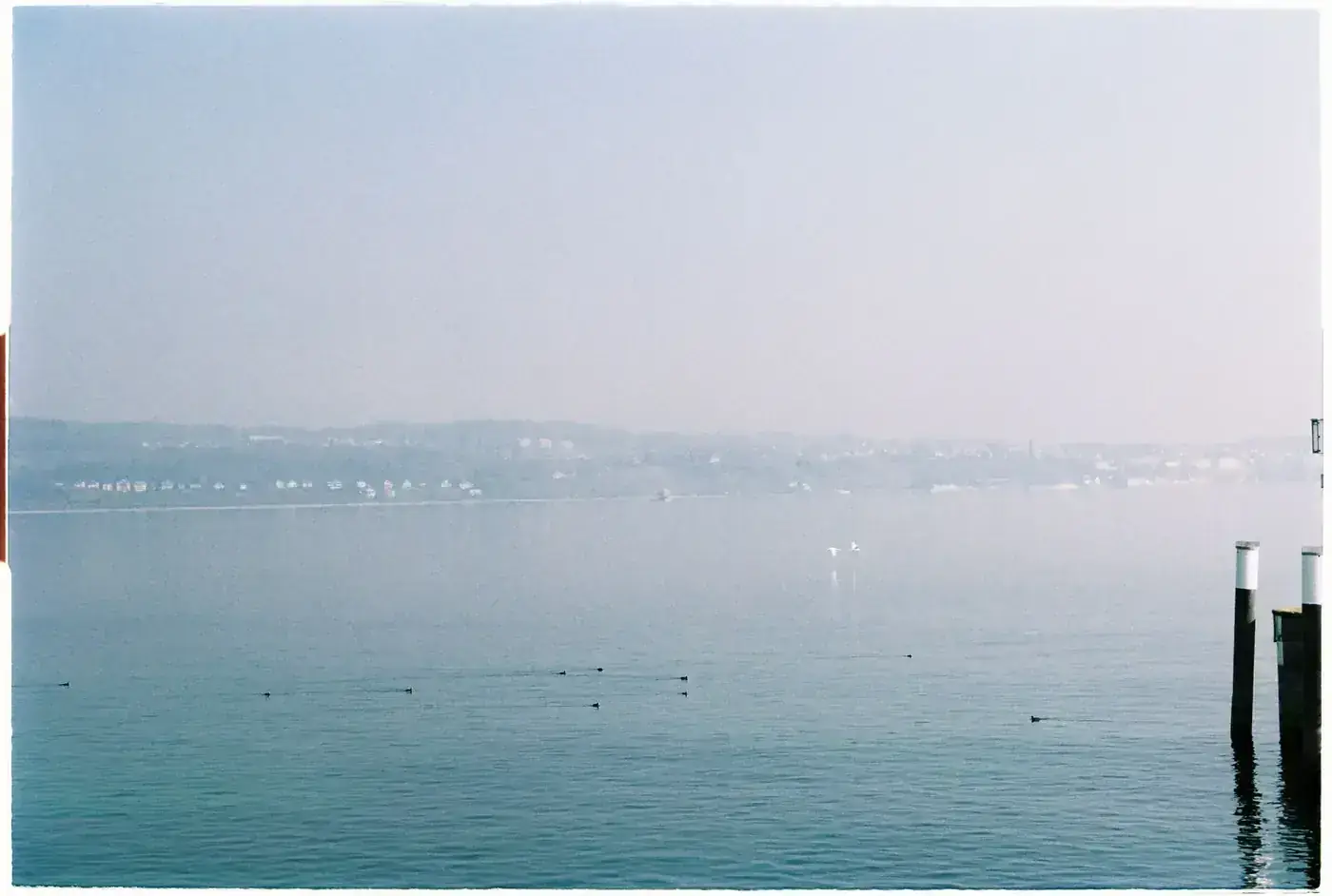 Serene landscape of Lake Constance with distant view of Meersburg, Germany in a calming blue tone.