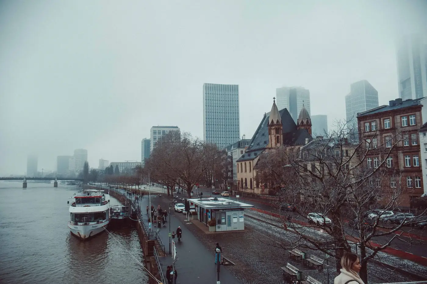 Capture of foggy Frankfurt skyline along the Main River with historic and modern buildings.