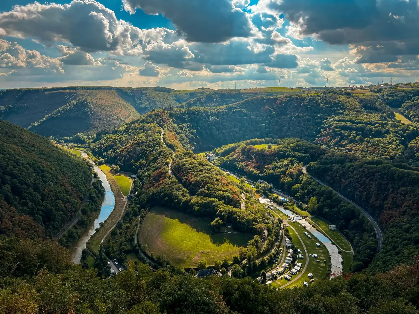 A breathtaking aerial view of a lush, green valley with a winding river under a cloudy sky.