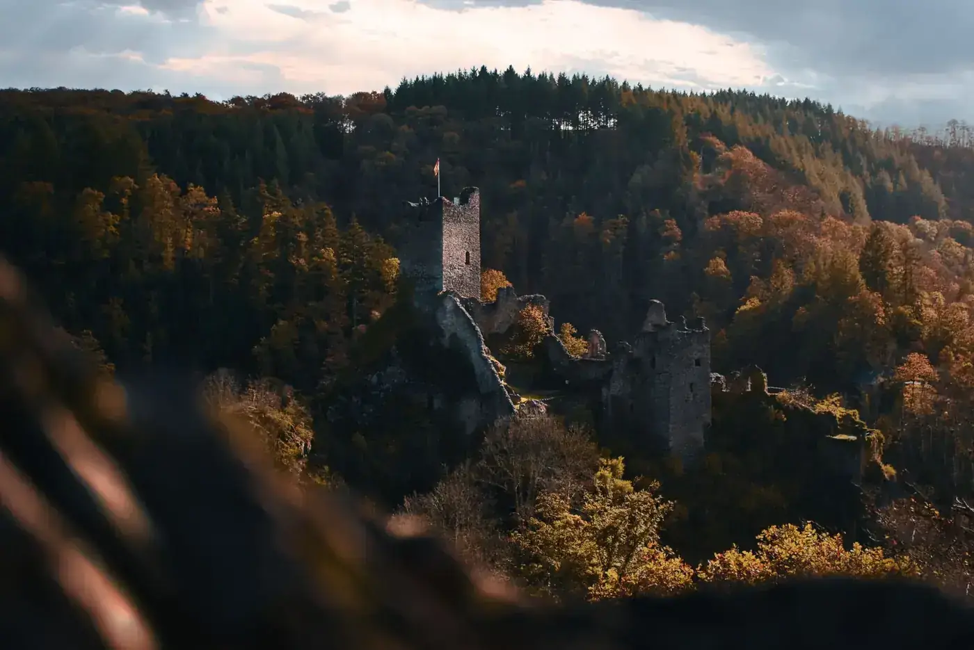 Ruins of Manderscheid Castle surrounded by autumnal forest in Germany.