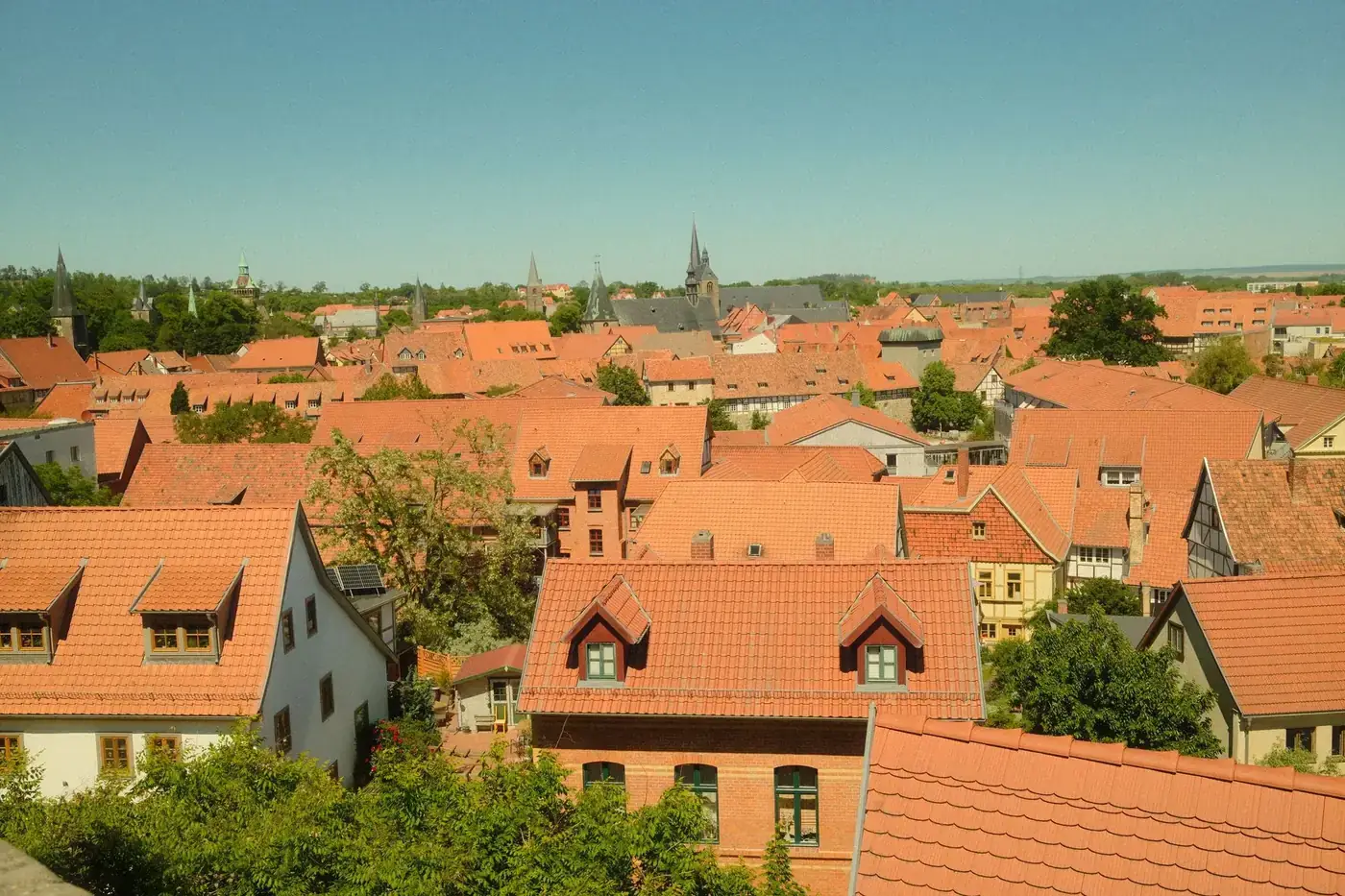 Aerial view of Quedlinburg showcasing red rooftops and historic architecture under a clear sky.