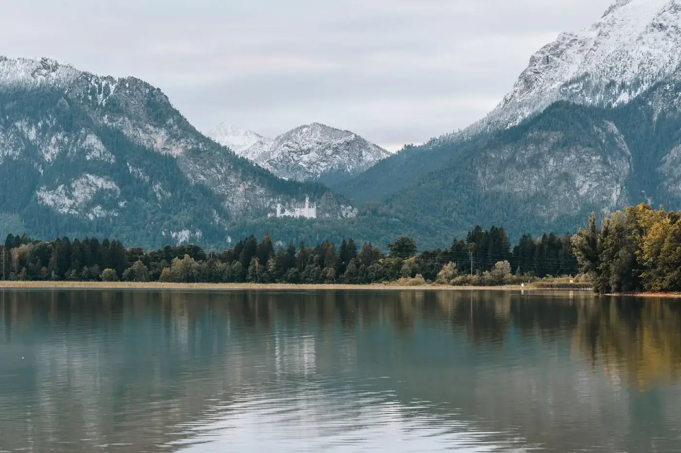 Tranquil landscape with Neuschwanstein Castle nestled in the Bavarian Alps, reflecting on the calm waters of Alpsee Lake