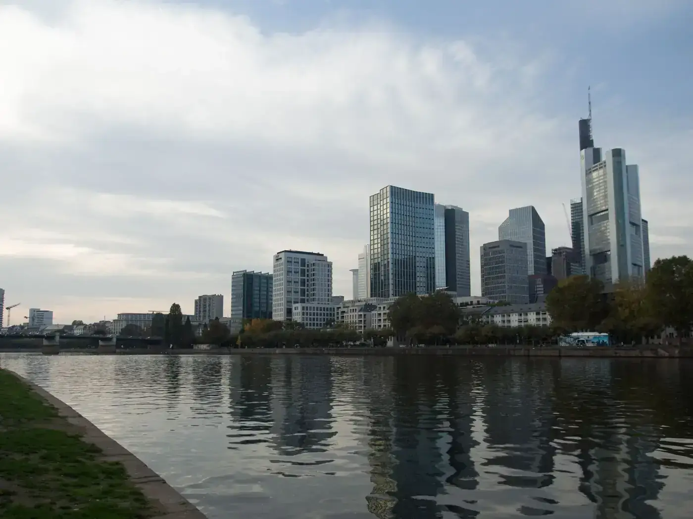 Modern skyscrapers reflecting in the river in Frankfurt cityscape.