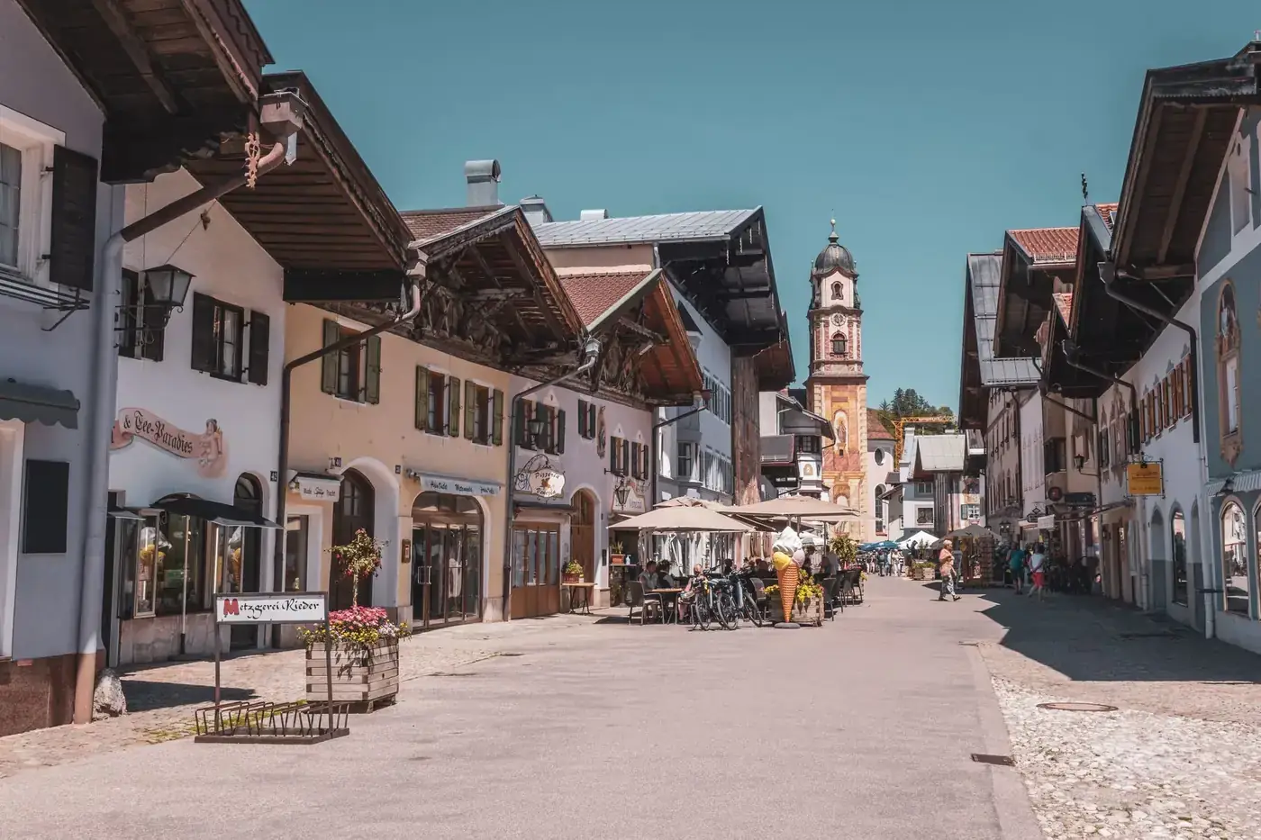 A picturesque street in Mittenwald, Bavaria, showcasing traditional architecture and vibrant summer life.