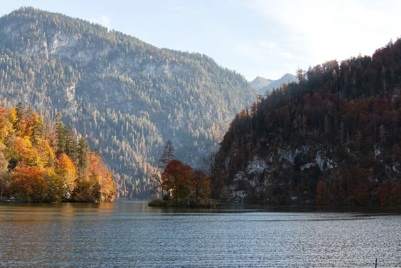 Serene lake with vibrant autumn foliage and mountainous backdrop.