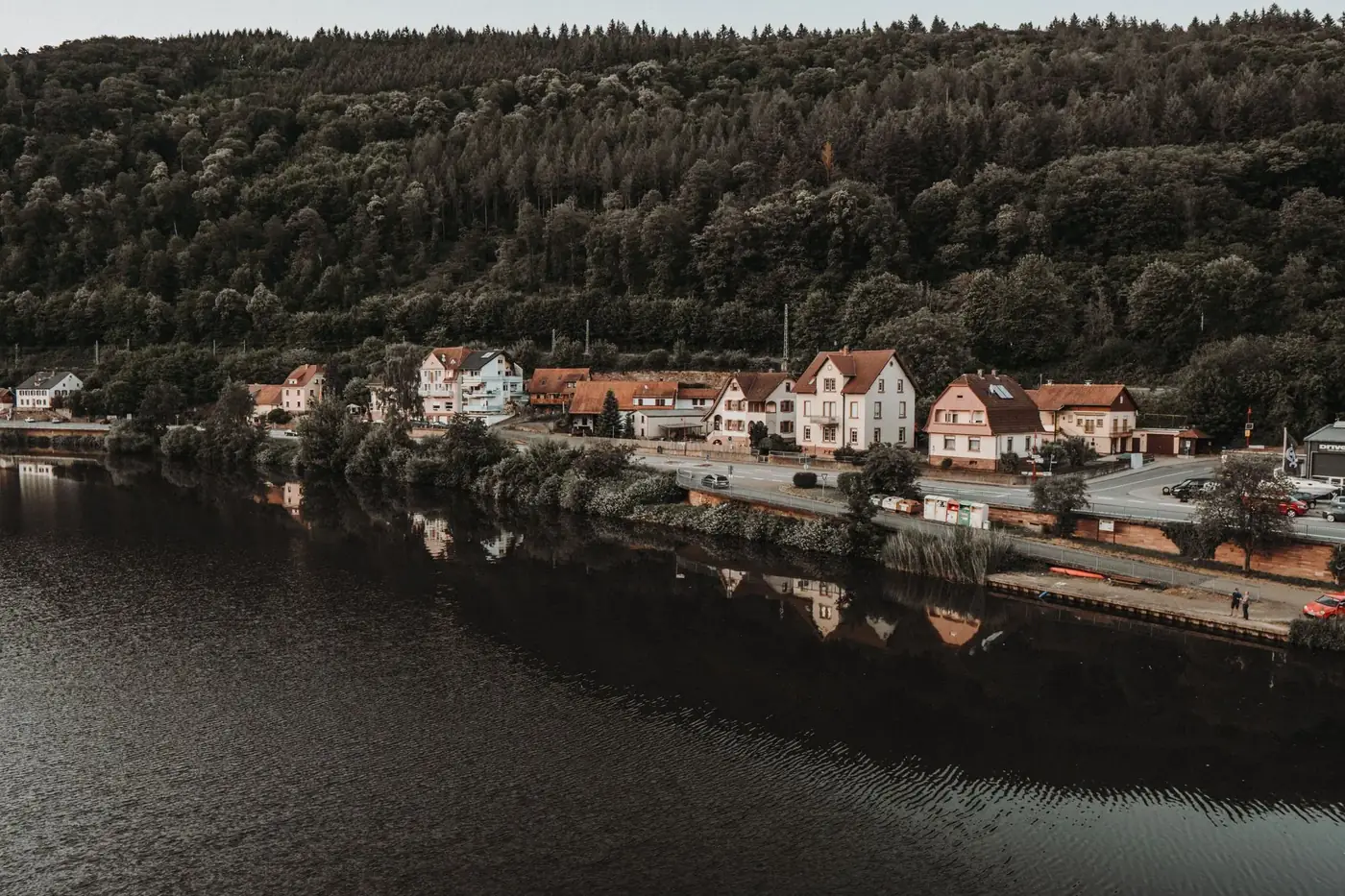 Quiet European town nestled between lush forests and a serene river, reflecting beauty and tranquility.