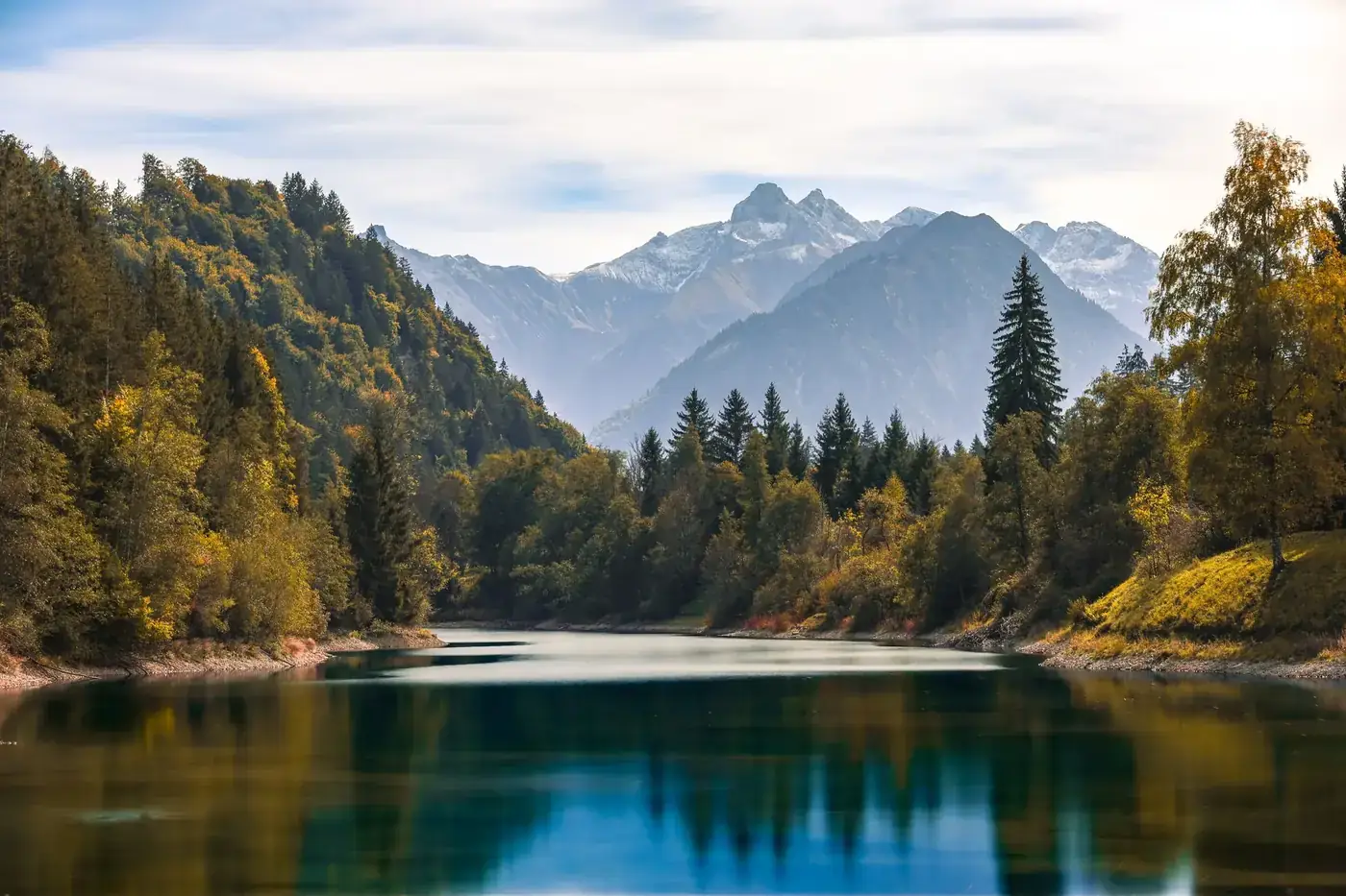Explore the tranquil autumn scenery of Fischen im Allgäu with mountains and a serene river.