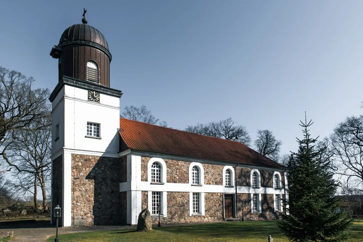 Charming village church with steeple in Gülzow, Germany, surrounded by nature.