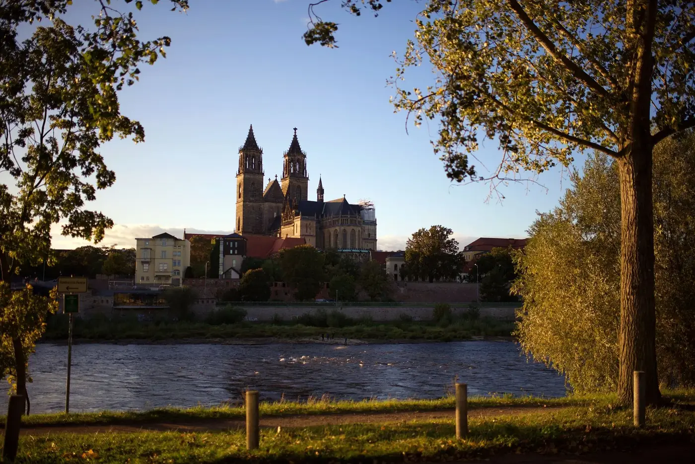 Scenic view of Magdeburg Cathedral and Elbe River at sunset, highlighting urban beauty.