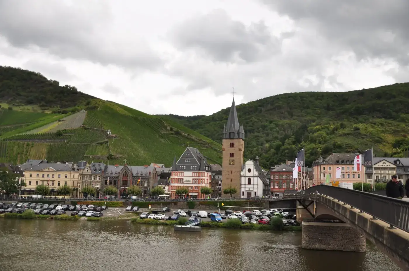 Scenic view of Bernkastel-Kues with historic buildings, vineyard, and bridge over the Moselle River.