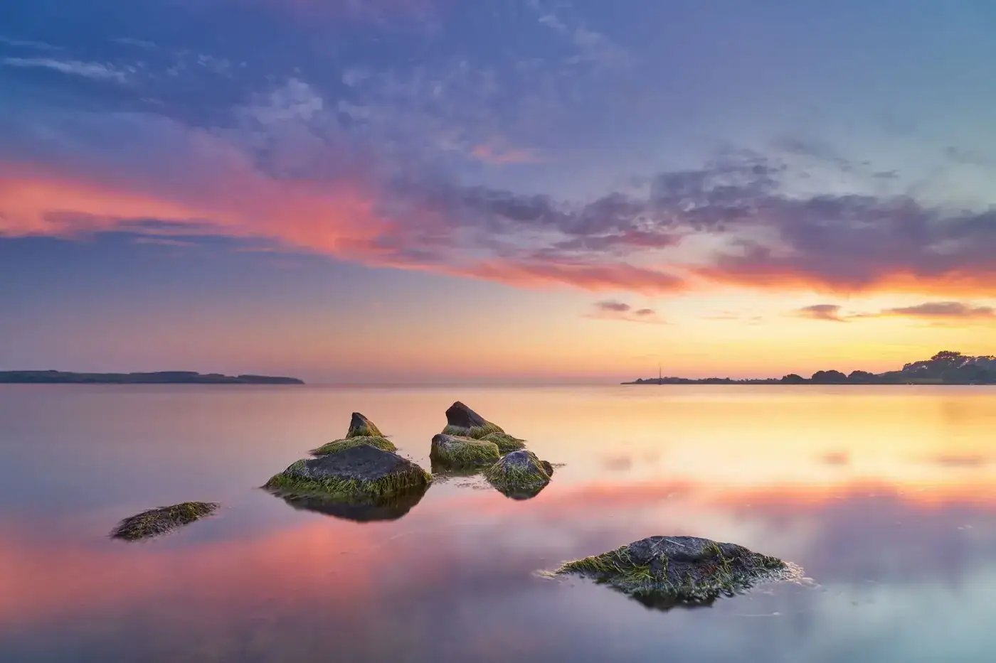 Stunning sunset over calm waters in Baabe, Germany, with vibrant sky and serene atmosphere.