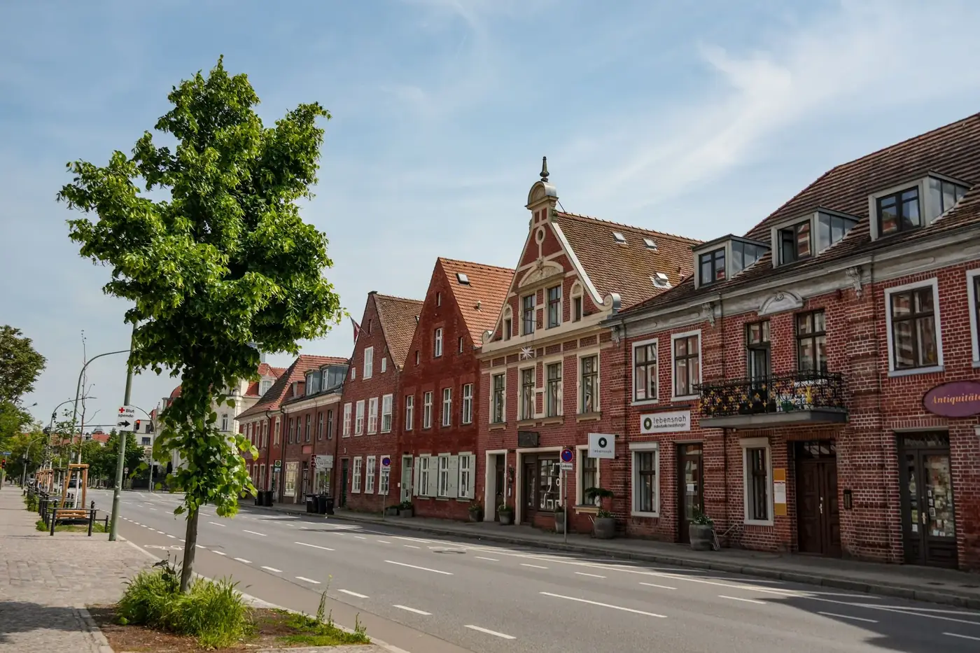 Charming street in Potsdam, Germany with red brick architecture and clear blue skies.