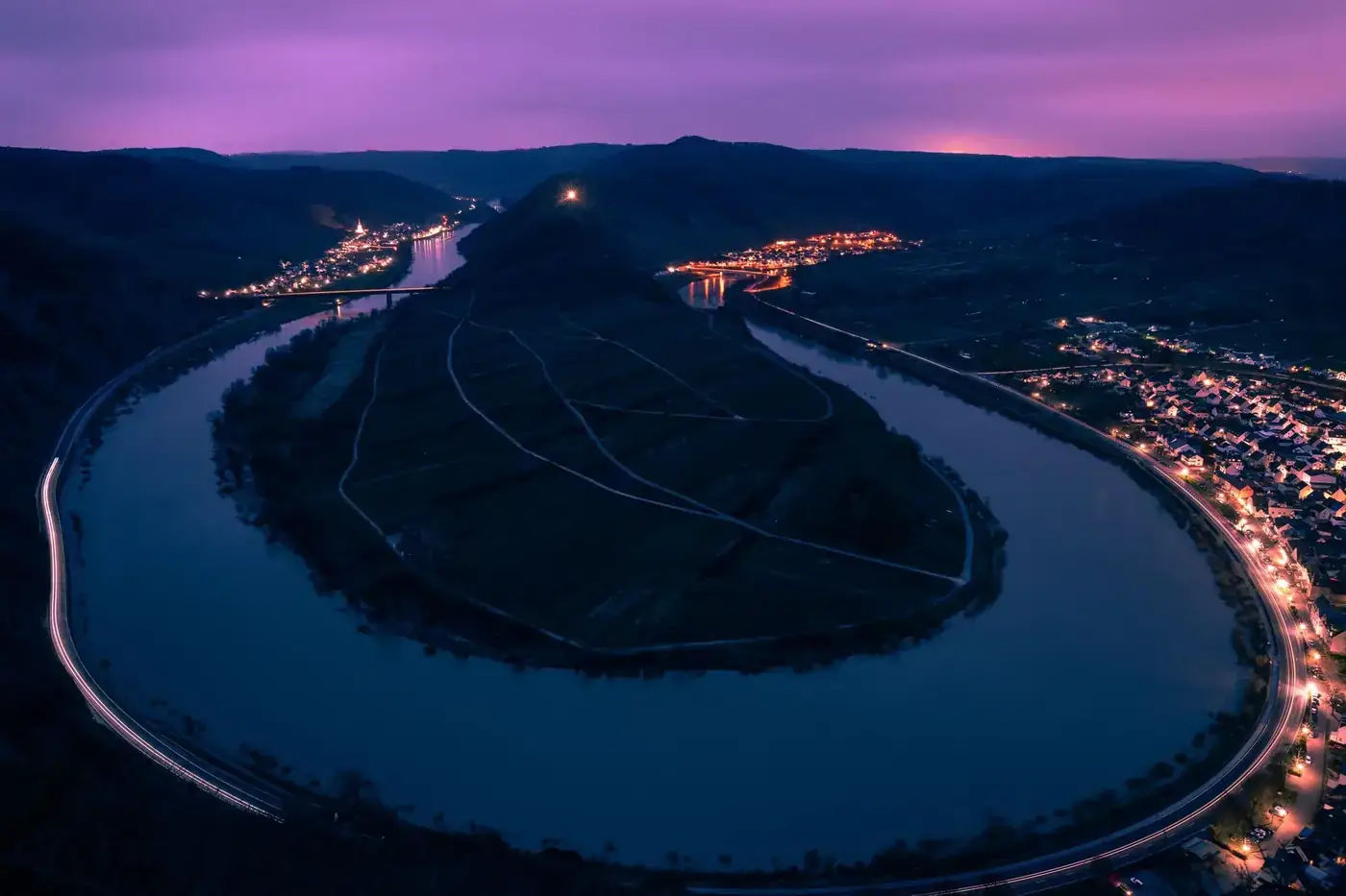 A breathtaking night-time aerial shot of the Moselle River bend in Bremm, Germany, illuminated beautifully.