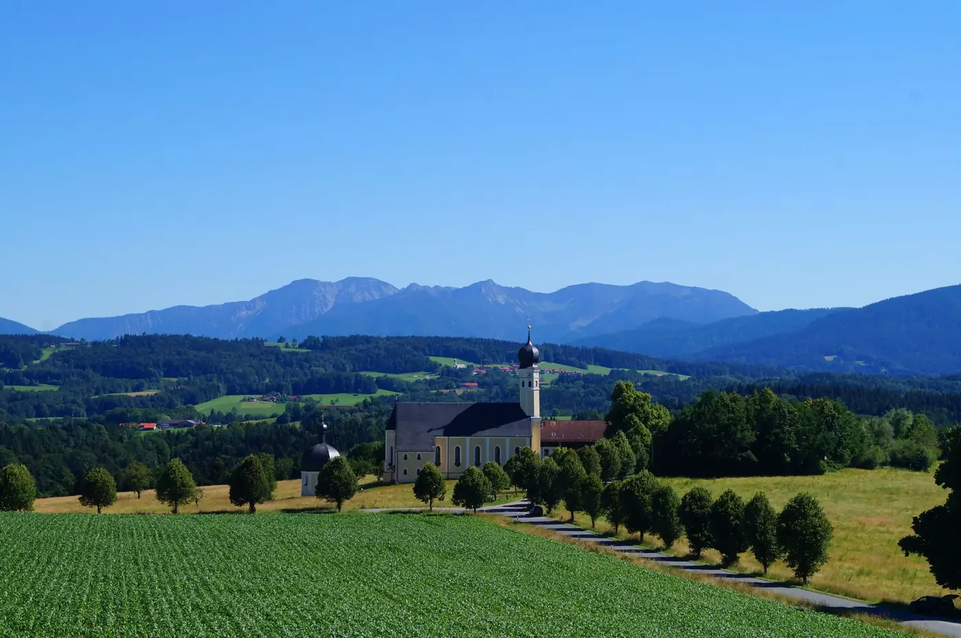 Serene rural landscape featuring a picturesque church amid lush fields and distant mountains.