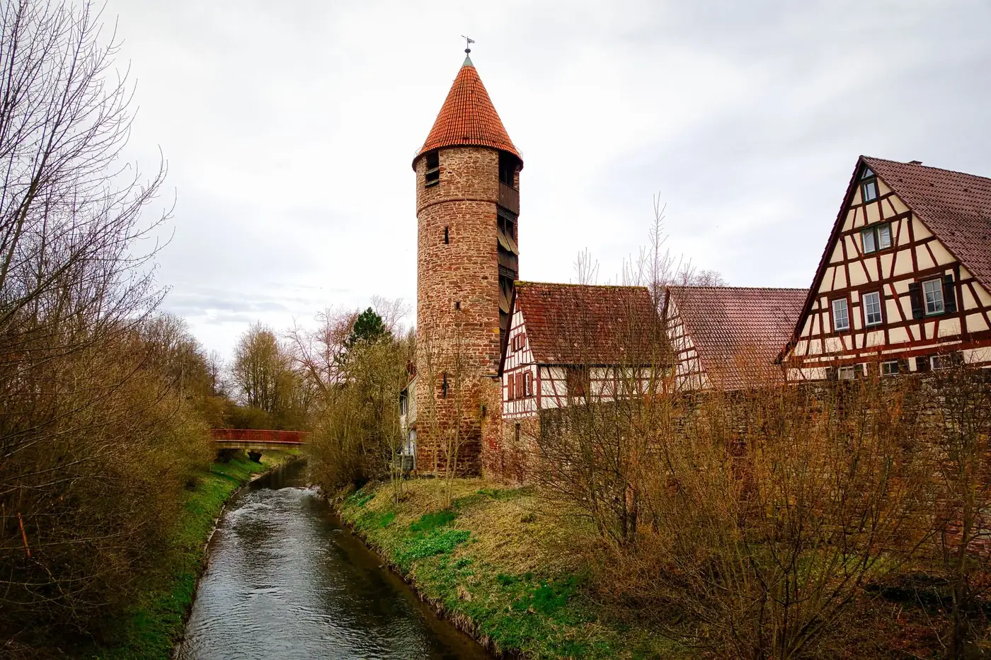 Medieval tower and half-timbered houses by a stream in Weil der Stadt, Germany during early spring.