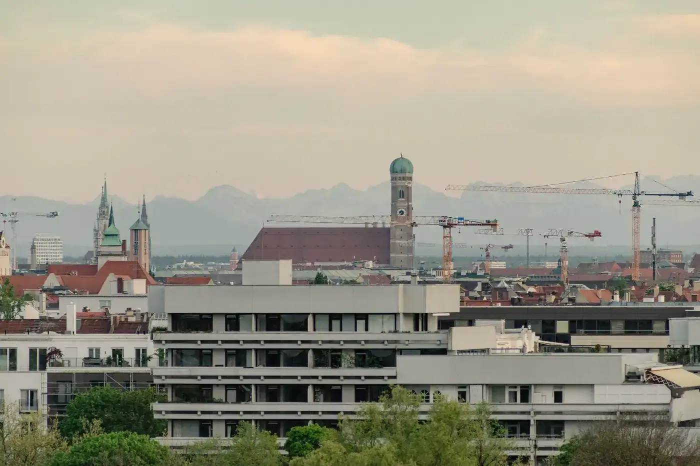 Scenic view of Munich skyline featuring the Frauenkirche and surrounding architecture at sunset.