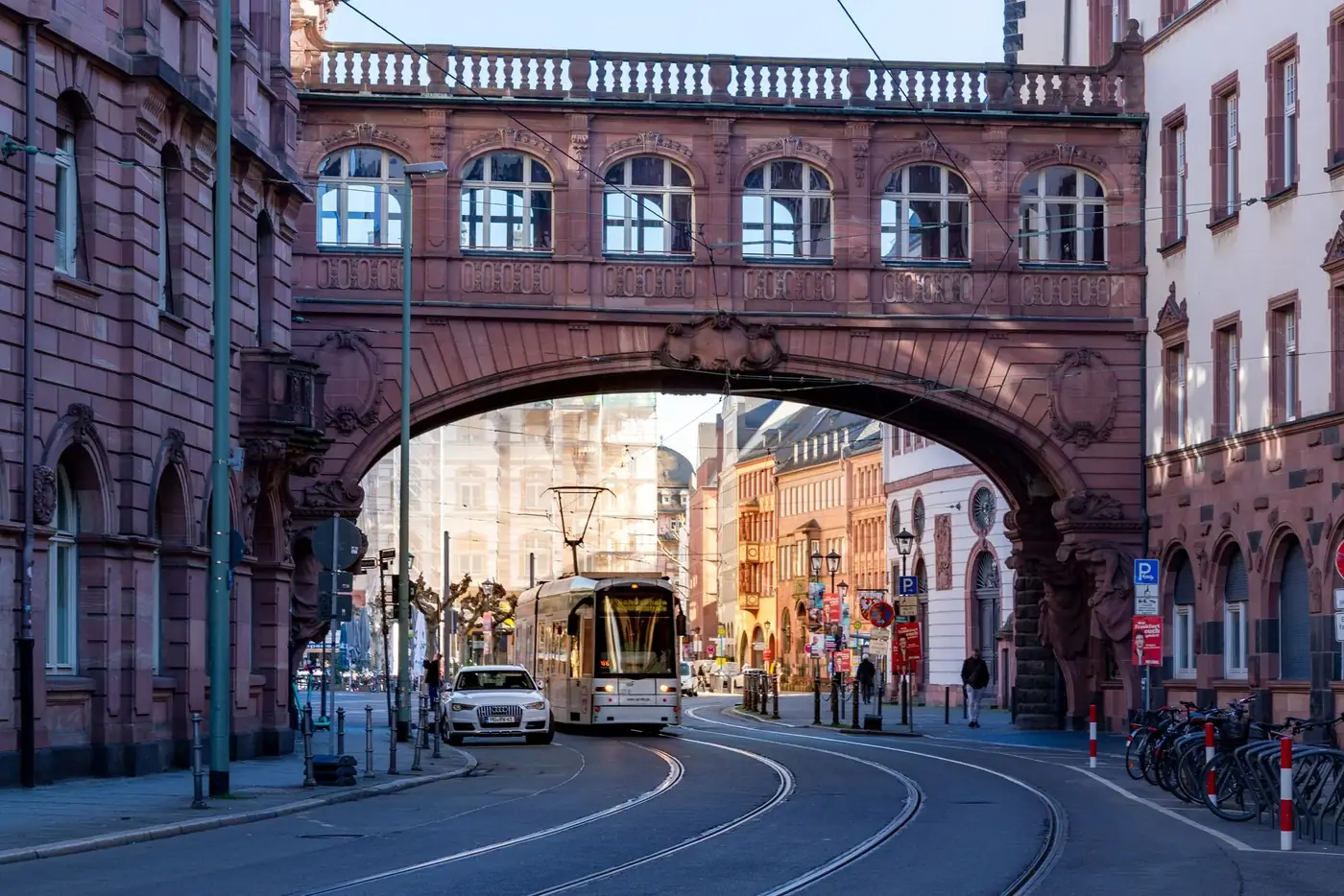 A tram passing under a historic archway on a sunny day in Frankfurt, Germany.