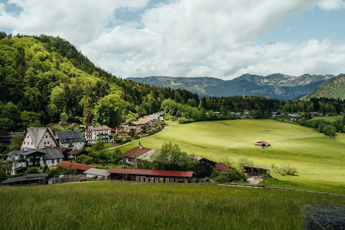 Idyllic rural landscape with lush green hills, mountains, and a charming village.