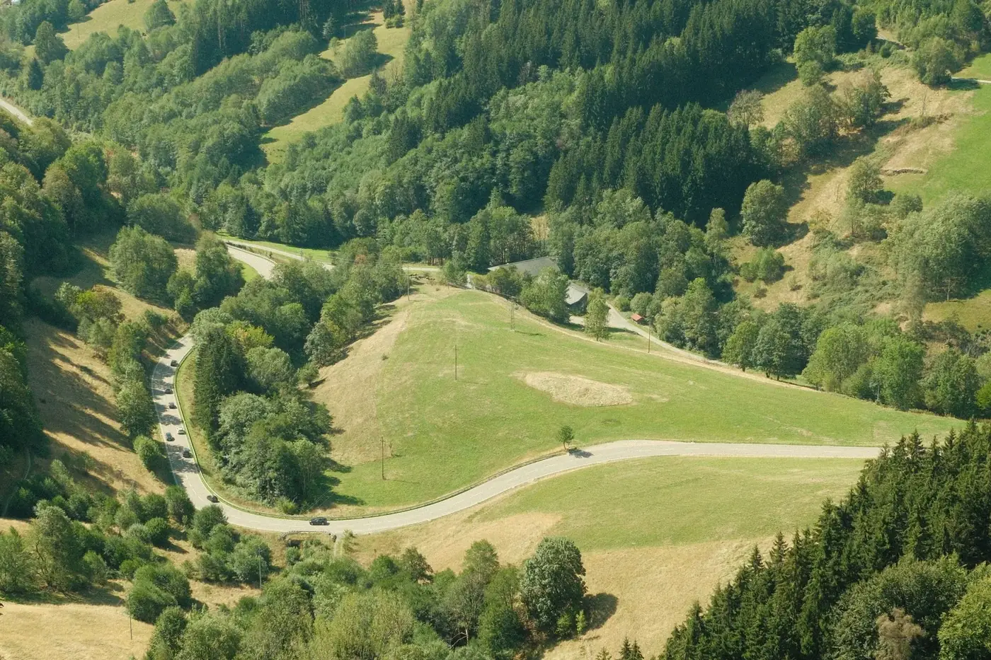 Aerial shot of winding road through lush Black Forest landscape in Germany, showcasing beautiful greenery and hills.