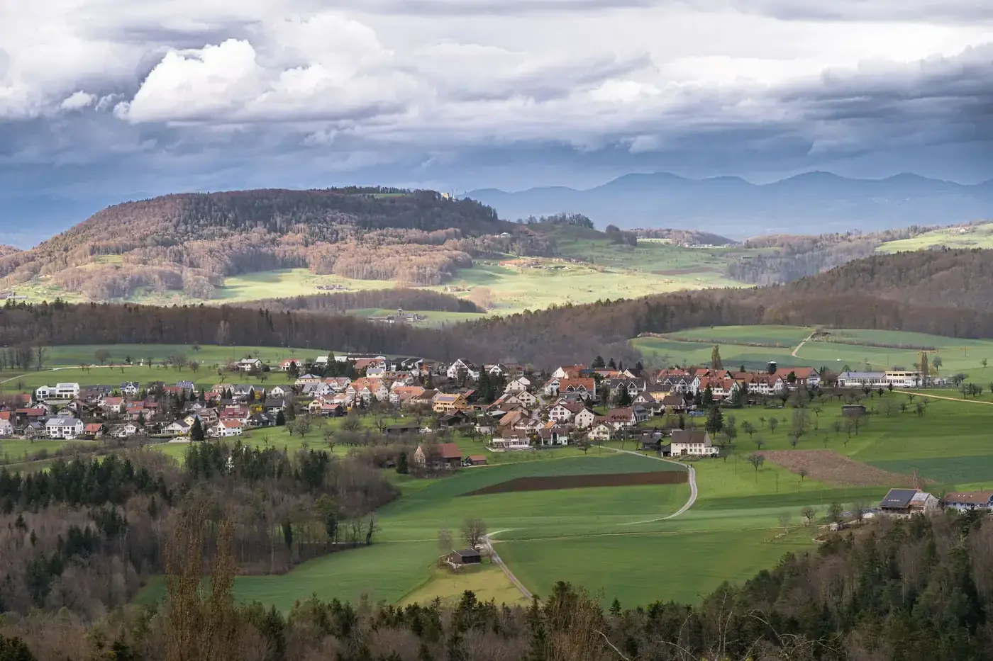 A scenic view of a mountain village surrounded by autumn colors and rolling hills.