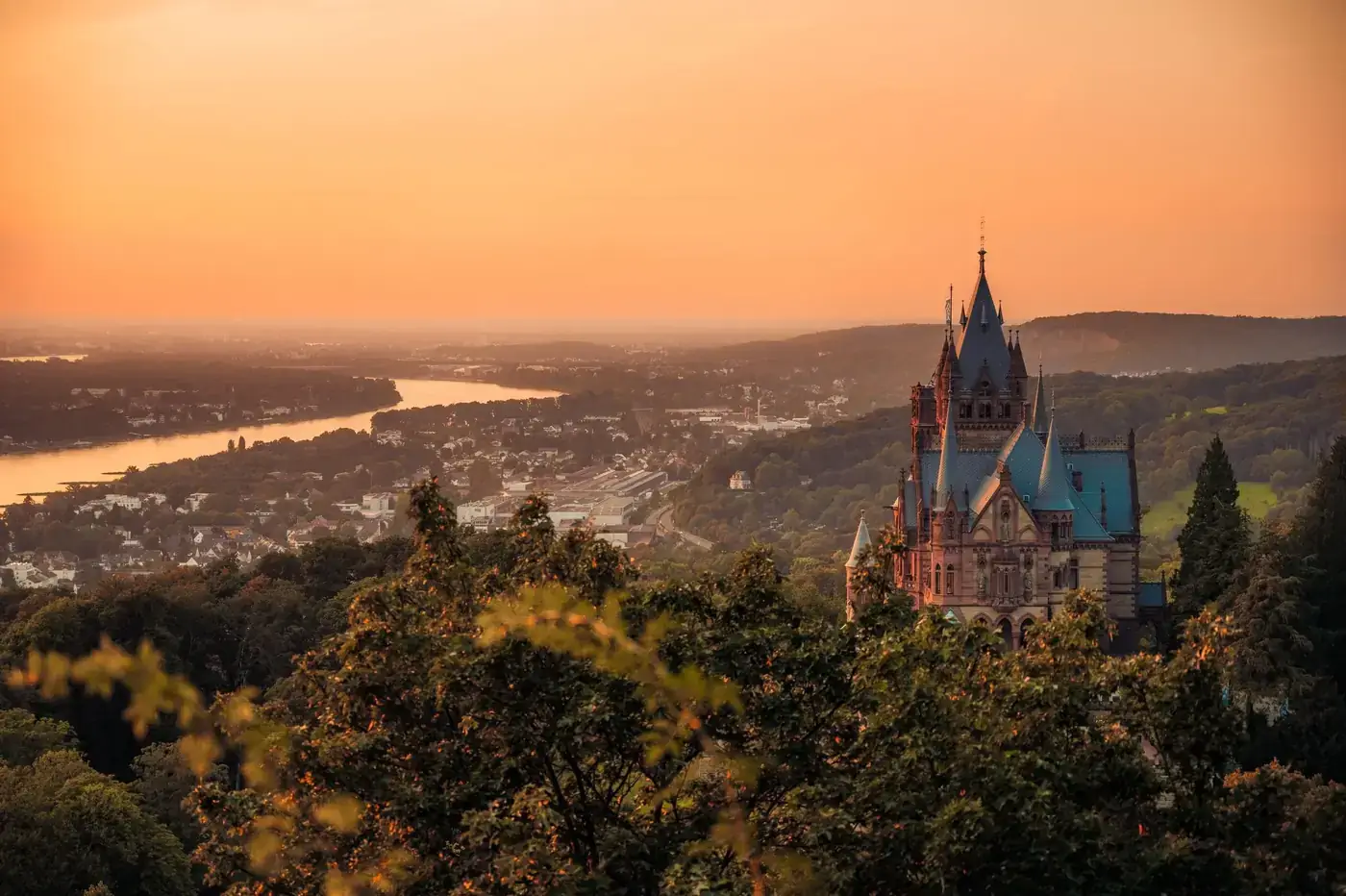 Captivating view of Schloss Drachenburg and Rhine Valley under a warm sunset glow.