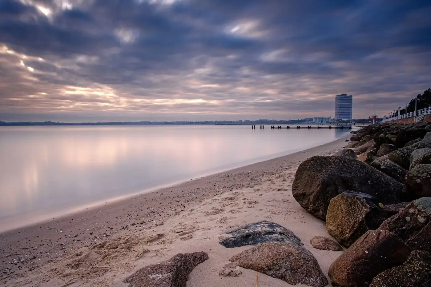 Calm beach and rocks against a colorful sunset over the Baltic Sea, offering a tranquil scene.