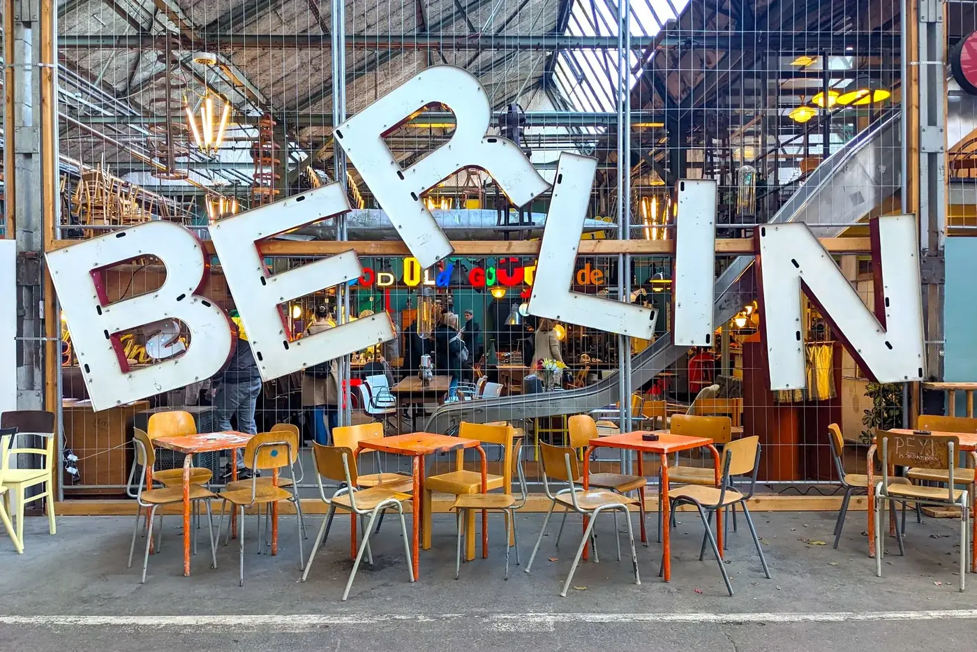 Colorful vintage shop entrance with Berlin sign and retro tables and chairs.