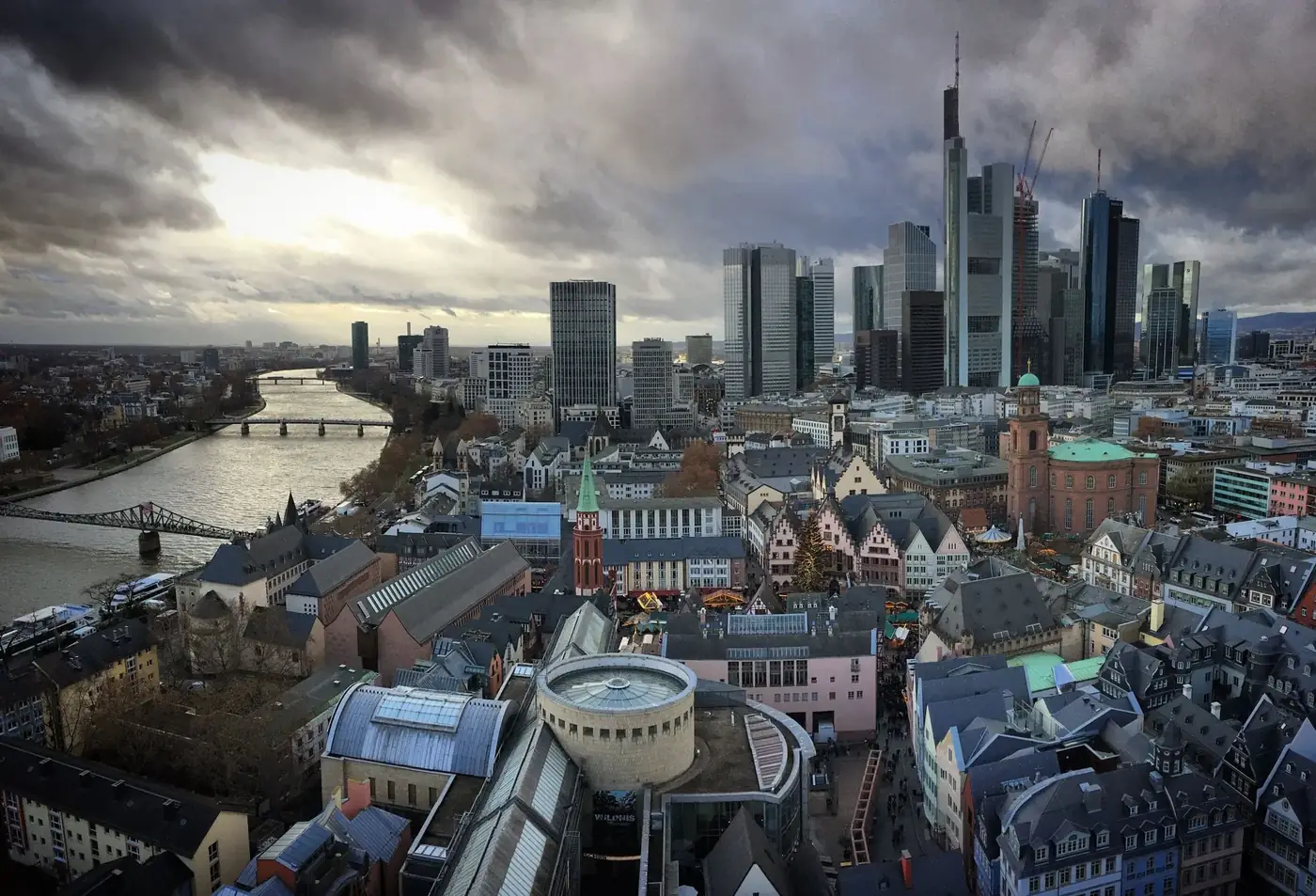 Aerial view of Frankfurt's modern skyline and historic center along the Main river at twilight.