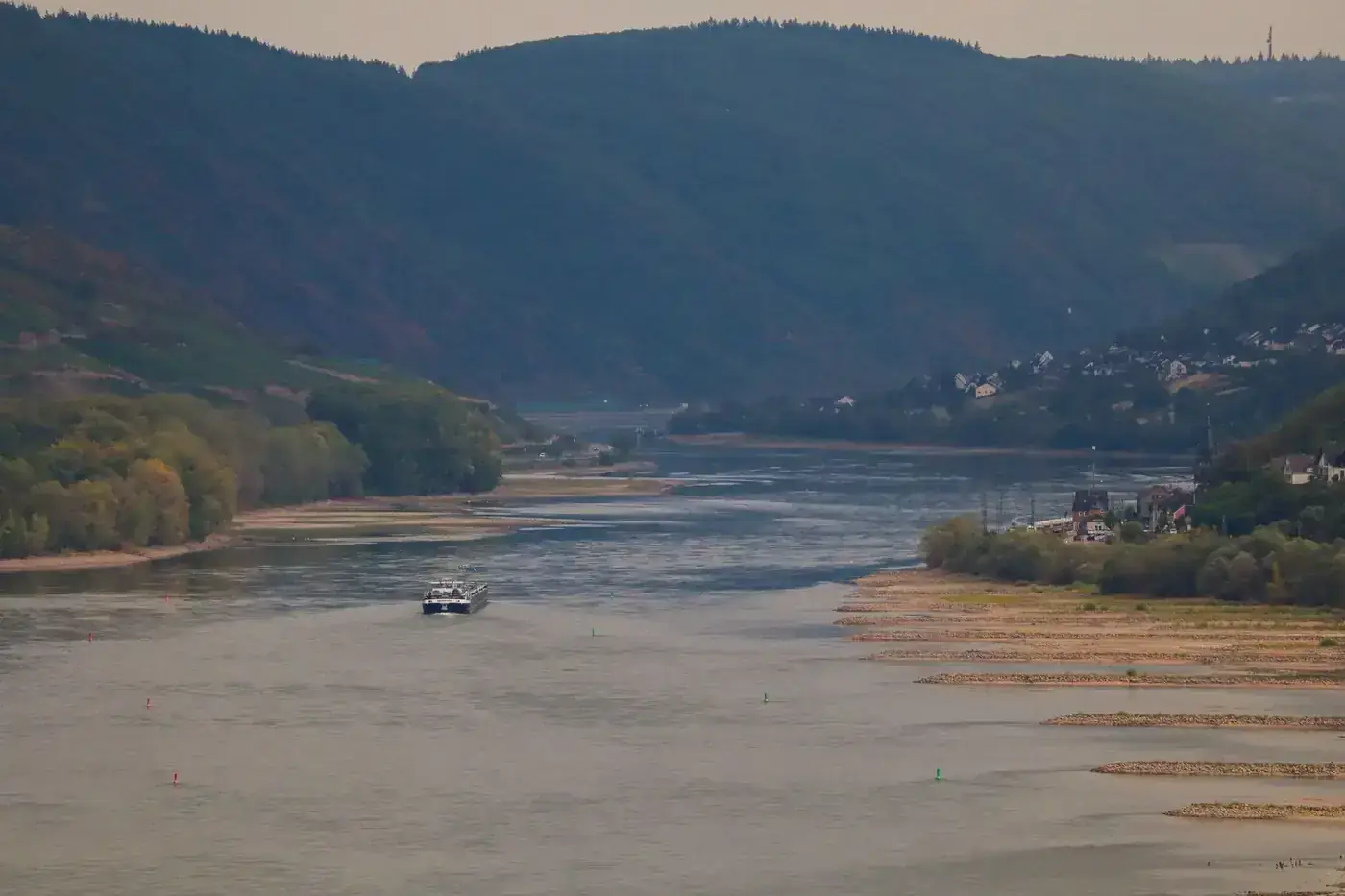 Picturesque landscape of the Rhine River with a boat and green hills in Bacharach, Germany.