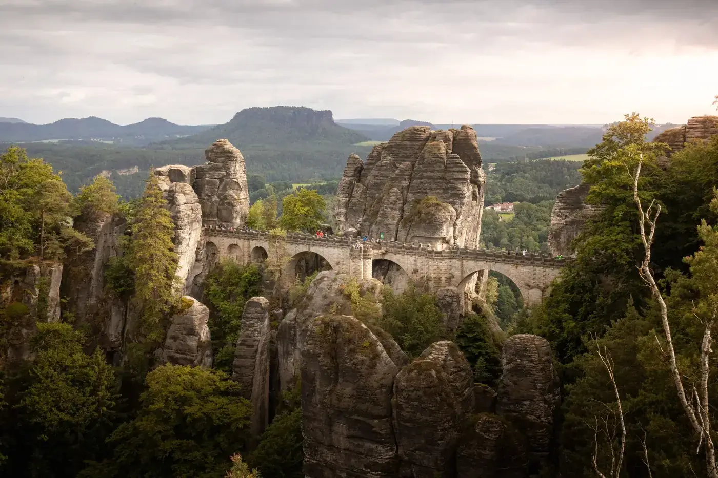Beautiful view of the historic Bastei Bridge surrounded by rock formations and forest in Saxony, Germany.