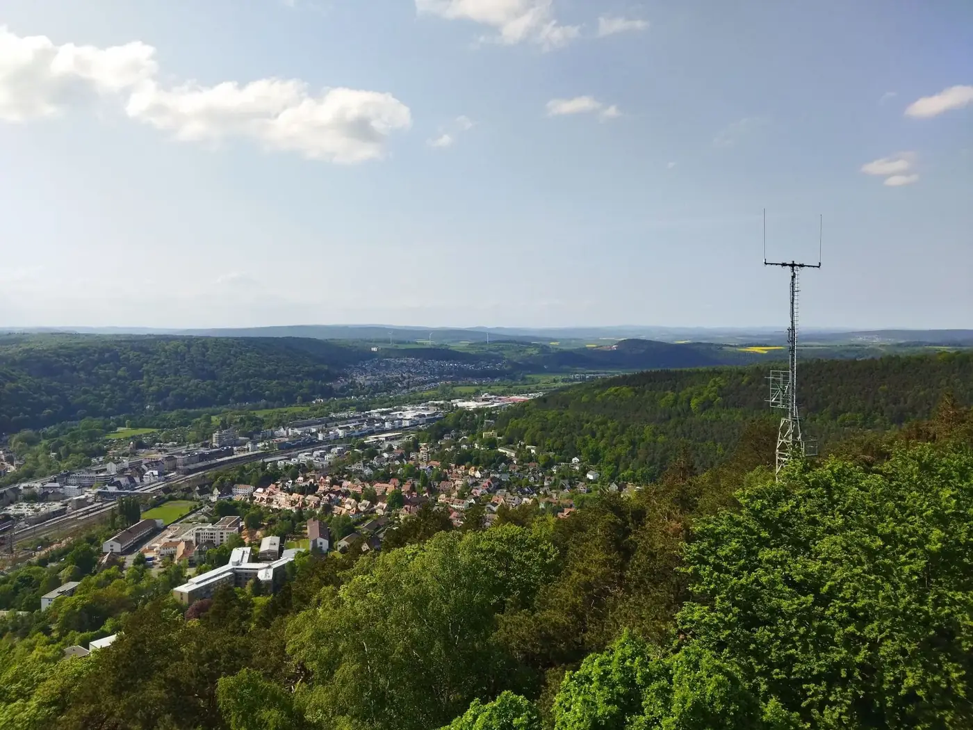 Aerial view of cityscape with lush forests and clear blue skies.
