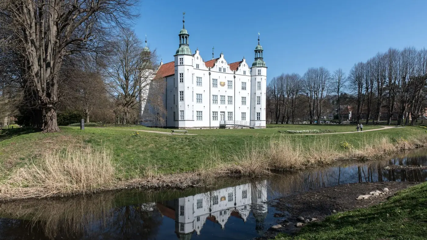 Ahrensburg Castle in Schleswig-Holstein, Germany with a perfect reflection in a nearby pond.