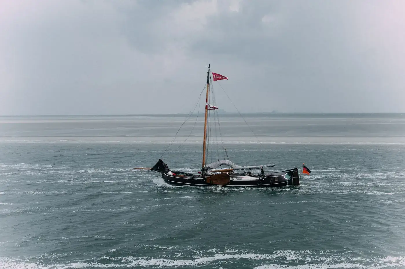 A classic wooden sailboat floats on the serene waters of Borkum, Germany.