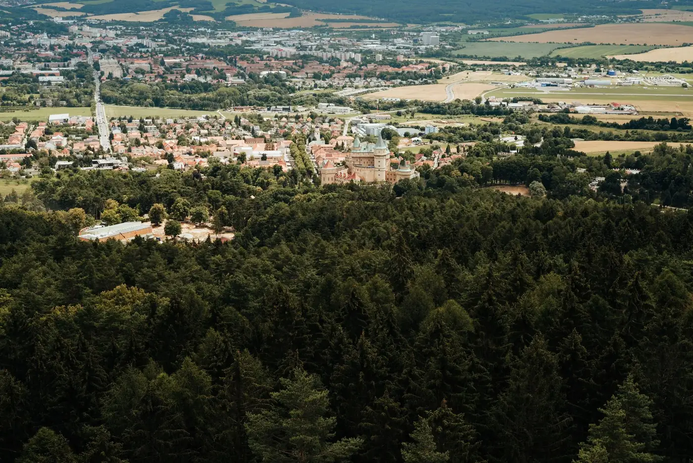 Aerial view capturing the scenic Bojnice Castle surrounded by lush greenery in Slovensko.