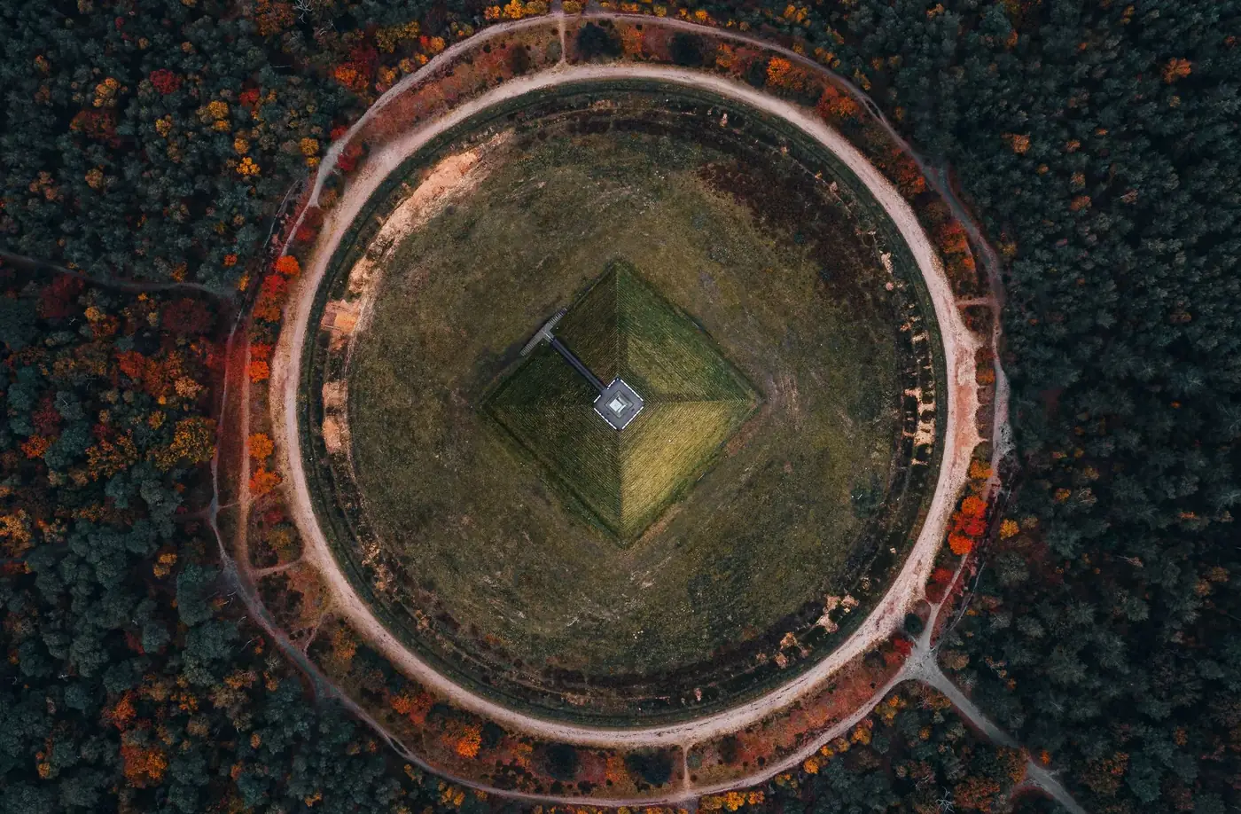Stunning aerial photo of a circular forest revealing autumn hues and a central landmark.
