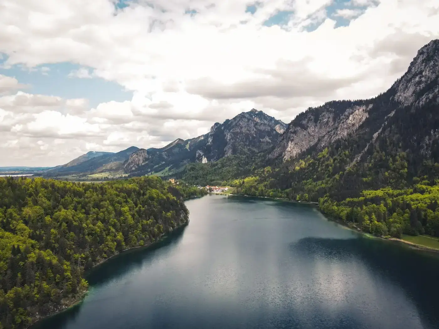Stunning aerial shot of a lake nestled among lush green forests and majestic mountains.