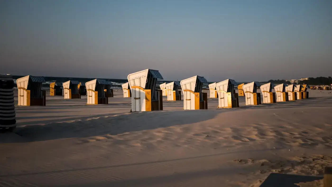 Rows of small identical wooden constructions in desert with dry sandy surface and loose texture under sky with horizon l