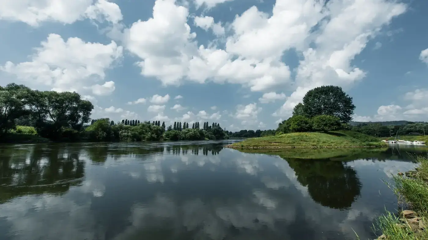 Serene riverside panorama of Weser in Höxter with lush greenery and reflective waters.