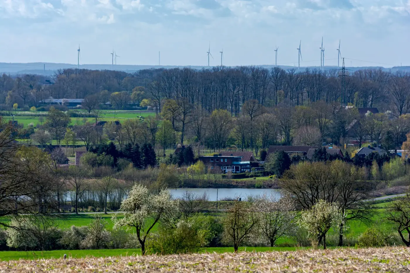 Beautiful springtime countryside view of Coesfeld, Germany featuring wind turbines and lush greenery.