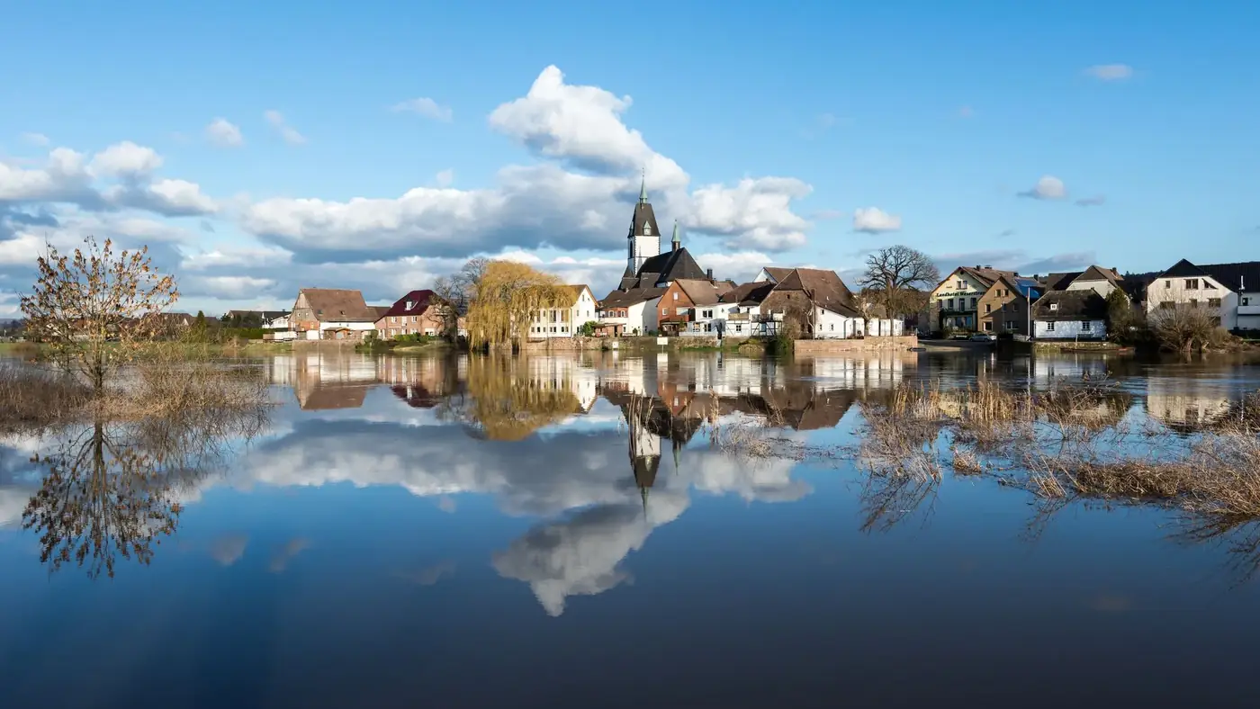 Peaceful riverfront village in Höxter, Germany with beautiful reflections on a clear day.