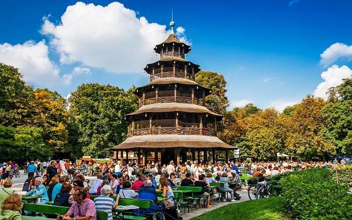 Mensen zitten in een prachtige tuin met een enorme pagode-achtige structuur 